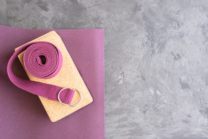 Open yoga mat with cork  block and yoga belt. Yoga practice props background. Copy space.